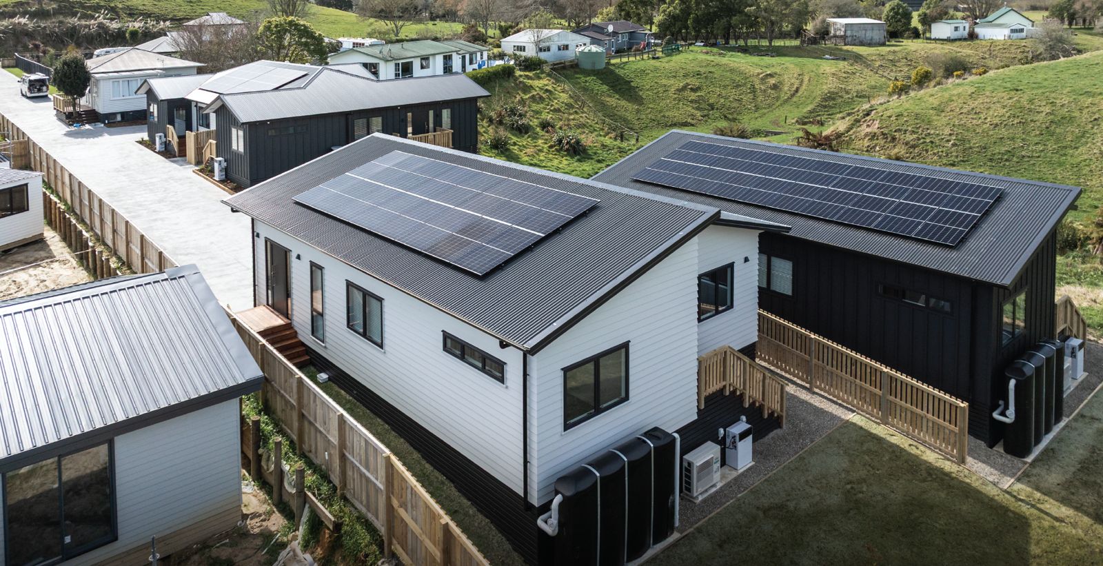 New homes on a rural-edge section with rolling green hills